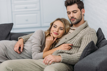 affectionate heterosexual couple lying on sofa in living room