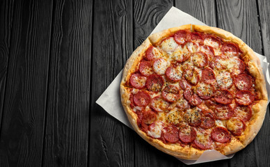 pepperoni pizza on dark black wooden board, top view, place for text, traditional italian pizza