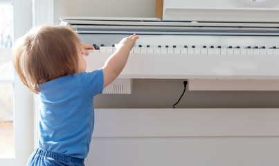 Fototapeta na wymiar Toddler boy excited to reach up and play the piano