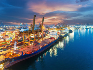 Container ship from sea port warehouse with working crane bridge unloading containers shipment at dusk. Suitable use for transport or import export to global logistics concept. - obrazy, fototapety, plakaty