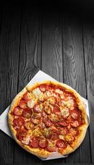 pepperoni pizza on dark black wooden board, top view, place for text, traditional italian pizza