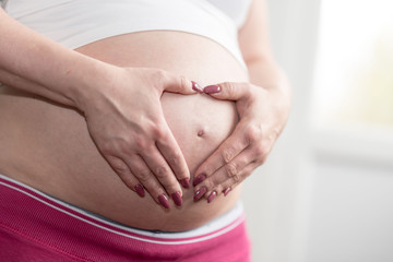 Pregnant belly with hands in heart shape