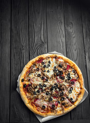 traditional italian pizza on dark black wooden board, top view, place for text