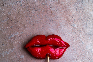 Plastic surgery concept. Cropped close up photo of big red lips candy on grey background