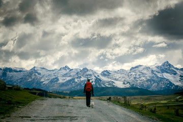 Persona caminando sola con dos perros en una carretera de montaña