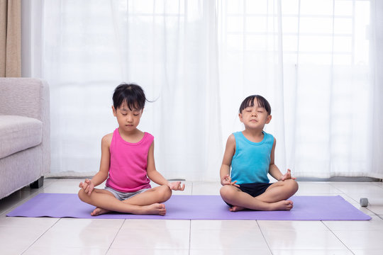 Asian Chinese little sisters practicing yoga pose on a mat © Tan Kian Khoon