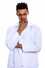 Studio shot of young African man doctor thinking with hand on ch