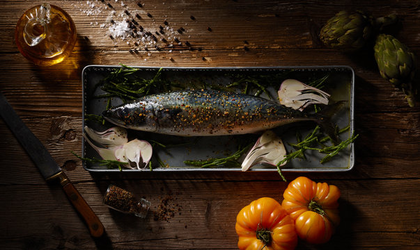 Raw fish on baking pan on wooden table
