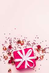 Christmas greeting card with gift and balls confetti on pastel background