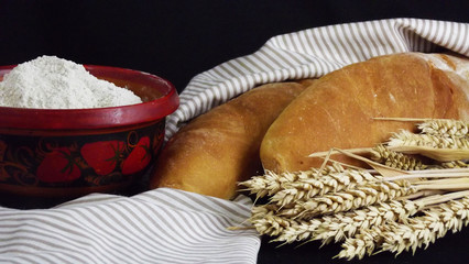 Delicious fresh homemade bread and ears on black background.