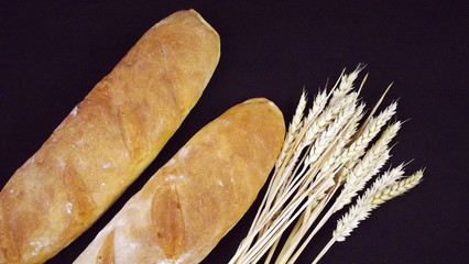 Delicious fresh homemade bread and ears on black background.