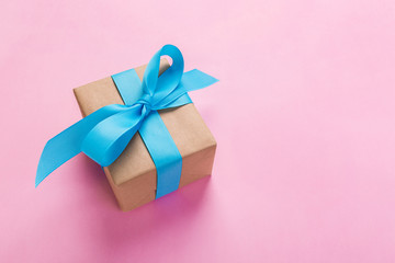 gift wrapped and decorated with blue bow on pink background with copy space. Flat lay, top view