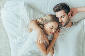 top view of beautiful young couple sleeping together and hugging in bed at home - Powered by Adobe