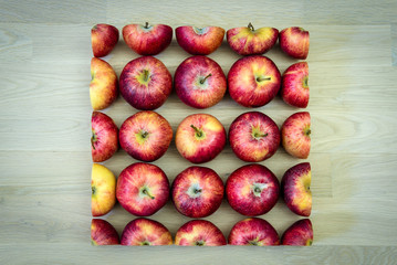 Äpfel im Quadrat auf hellem Holzboden