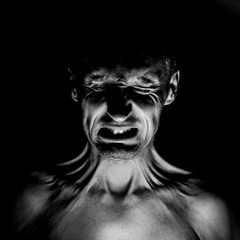 Stylish dark portrait of feared adult caucasian man who wrinkles his face. Fear and disgust concept. Black and white shot, low key lighting.