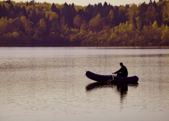 Fisherman catches fish. A man on a fishing trip with fishing rods and a rubber inflatable boat.