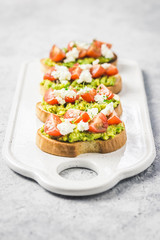 Avocado cherry tomatoes toasts on board. Selective focus, space for text.