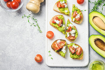 Avocado cherry tomatoes feta cheese toasts on board. Top view, space for text.