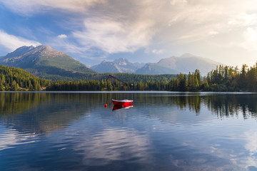 Peaceful mountain scene with mountain hotel next to a lake with boat. Scenic view of Strbske Pleso, High Tatras National Park, Slovakia.