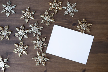 White form card for holiday greetings with Christmas stars decorations at wooden background. Space for text or painting.