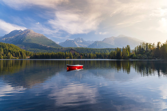 Peaceful mountain scene with mountain hotel next to a lake with boat. Scenic view of Strbske Pleso, High Tatras National Park, Slovakia.