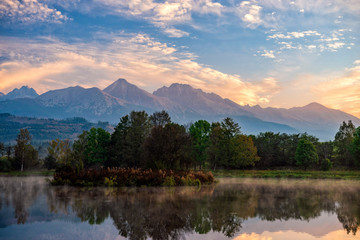Obraz premium Peaceful autumn landscape with calm lake, colorful trees and low hanging fog/mist in a autumn time.