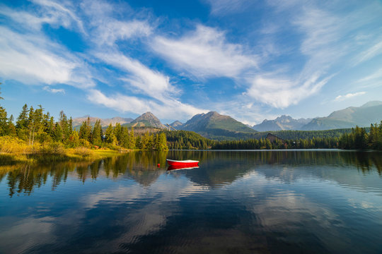 Peaceful mountain scene with mountain hotel next to a lake with boat. Scenic view of Strbske Pleso, High Tatras National Park, Slovakia.