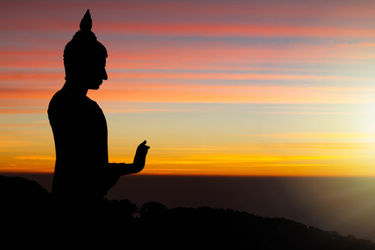 Silhouette of Buddha statue on sunrise background
