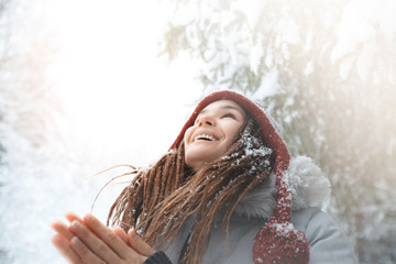 Young girl rejoices in snowfall  in forest