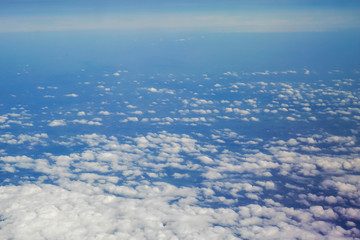 The sky and clouds and the view seen in the window of the plane.