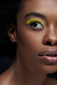 partial view of african american model with bright neon eye shadow isolated on black