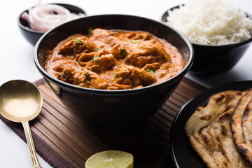 Murgh Makhani / Butter chicken tikka masala served with roti / Paratha and plain rice along with onion salad. selective focus