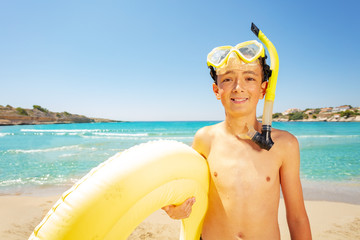 Boy in scuba mask with swimming ring on the beach