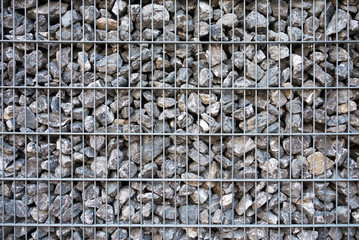 Close up of fence of stones, gray stones. Stones inside metal grating. Texture, background