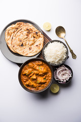 Murgh Makhani / Butter chicken tikka masala served with roti / Paratha and plain rice along with onion salad. selective focus