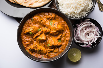 Murgh Makhani / Butter chicken tikka masala served with roti / Paratha and plain rice along with onion salad. selective focus