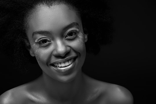 black and white photo of cheerful african american woman isolated on black