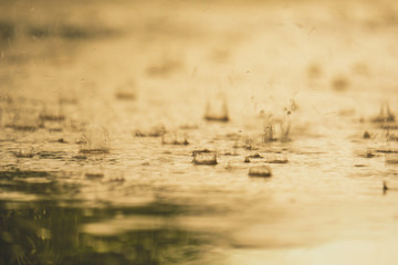 Vintage color tone of close up rain water drop splash falling to the floor in rainy season with Soft sunlight