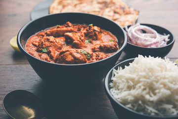 Murgh Makhani / Butter chicken tikka masala served with roti / Paratha and plain rice along with onion salad. selective focus