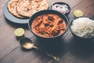 Murgh Makhani / Butter chicken tikka masala served with roti / Paratha and plain rice along with onion salad. selective focus