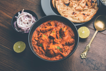 Murgh Makhani / Butter chicken tikka masala served with roti / Paratha and plain rice along with onion salad. selective focus