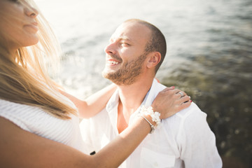 Obraz premium Just married wedding couple walking on the beach at sunset.