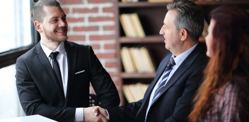 friendly handshake of business partners sitting at a Desk