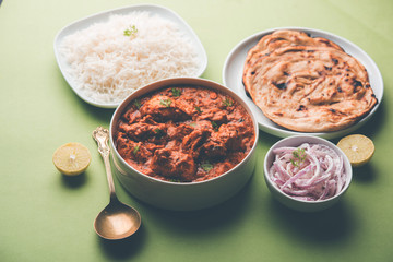 Murgh Makhani / Butter chicken tikka masala served with roti / Paratha and plain rice along with onion salad. selective focus
