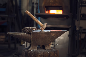 Mallet and gloves on an anvil in front of a furnace