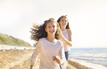 Mother and daughter having fun, running at the beach