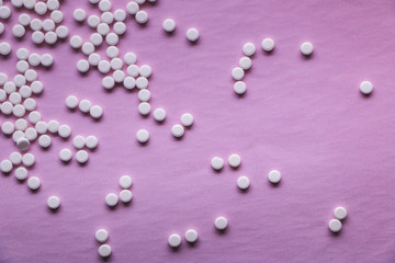 small white pills on a pink background. vitamins, drugs, antibiotics in the form of pills on a textural surface.