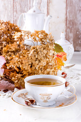 Tea in the rustic vintage Chic style. Garden tea Party. Teapot of dry flowers. Cup of tea with autumn decor on table, with hydrangea and pumpkin