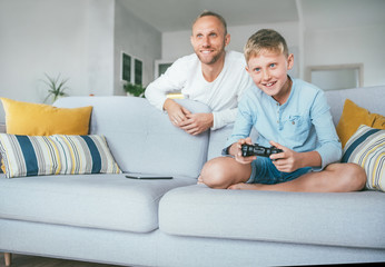 Father watching his son playing TV video game using the gamepad