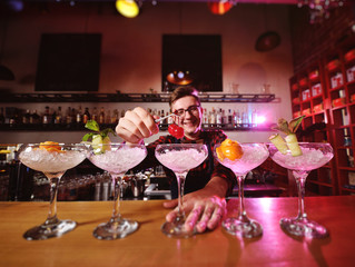 a handsome young bartender prepares cocktails and puts cherries for cocktails